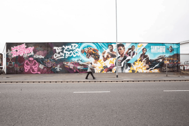 A Man Walking On The Side Of A Road With Graffiti On The Side